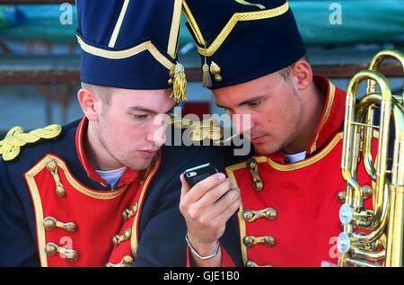 Bruxelles, Belgio. Il 15 agosto, 2016. Due soldati e guardare un telefono cellulare prima di iniziare il Saint Lambert marzo svoltasi a Cerfontaine, Belgio meridionale, 15 agosto 2016. L annuale Saint Lambert marzo emanata una scena dell'esercito di Napoleone in marcia nel sud del Belgio il lunedì. Le marche di Entre-Sambre-et-Meuse, una serie di arredi in stile marchigiano, compreso il Saint Lambert marzo nel sud del Belgio è stata incisa sul UNESCO lista rappresentativa del Patrimonio Culturale Immateriale dell' Umanità nel 2012. © Gong Bing/Xinhua/Alamy Live News Foto Stock