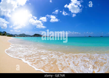Sole che splende su una spiaggia tropicale con sabbia bianca e verde turchese blu acqua Foto Stock