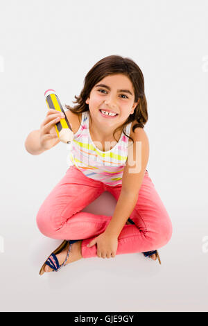 Bambina facendo un disegno con una matita grande nel pavimento Foto Stock