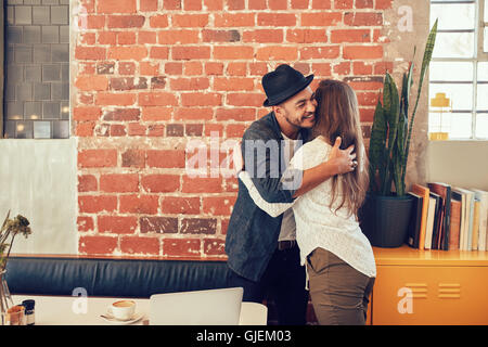 Ritratto di giovane uomo saluto una donna al cafe. Giovane uomo abbracciando la sua fidanzata a un coffee shop. Foto Stock