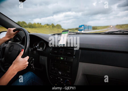 Le mani della donna guidatore sul volante di guida auto su strada in condizioni di tempo piovoso Foto Stock