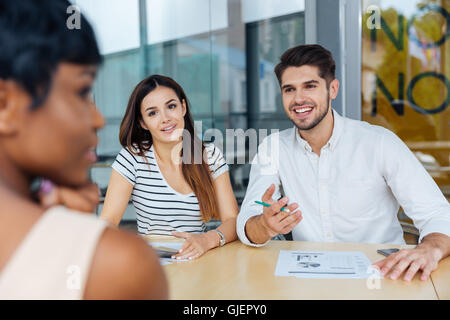 Felice del gruppo di giovani business partner per discutere le idee alla riunione in ufficio Foto Stock