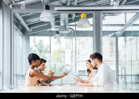 Un gruppo di giovani imprenditori a parlare e lavorare insieme in sala conferenze Foto Stock