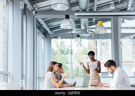 Un gruppo di giovani uomini di affari che a discutere di una relazione finanziaria e il nuovo progetto in sala conferenze Foto Stock