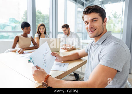 Felice successo giovane imprenditore lavora con i suoi colleghi in ufficio Foto Stock