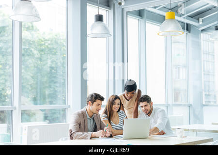 Gruppo multietnico di giovani uomini di affari che la creazione di presentazione e utilizzando laptop insieme in ufficio Foto Stock