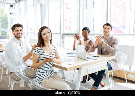 Gruppo multietnico di felice giovane gente di affari plaudendo alla riunione in ufficio Foto Stock