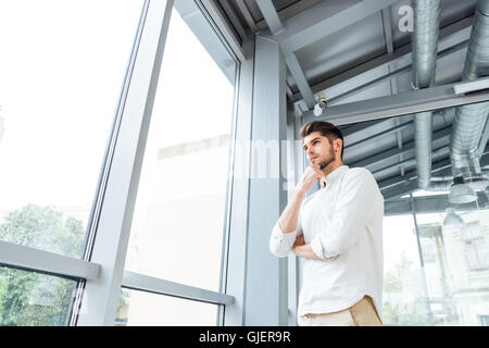Malinconici attrative giovane uomo di pensiero e guardando la finestra Foto Stock
