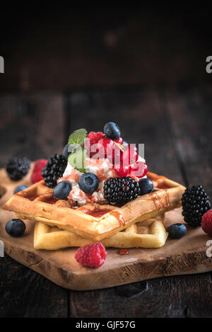 Tradizionale waffles belgi sulla tavola di legno con bacche e gelato sulla parte superiore Foto Stock
