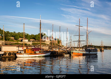 Tramonto sul porto di Oslo con molte antiche in legno barche a vela e la Fortezza di Akershus in background in Norvegia la città capitale. Foto Stock