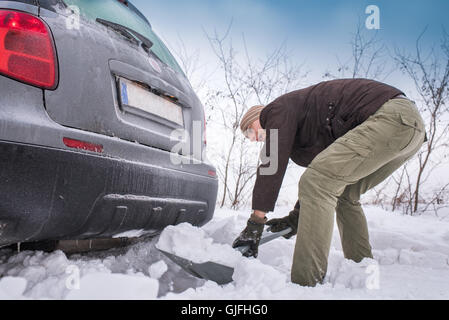 L uomo lo scavo fino bloccato in snow car Foto Stock