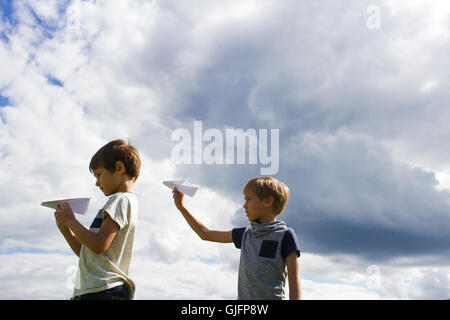 Ragazzi piccoli con piani di carta contro il cielo blu Foto Stock