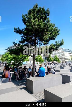 I turisti seduti sotto un albero presso il Memoriale dell'olocausto all'assassinato ebrei d'Europa, Berlino, Germania. Foto Stock