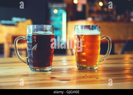 Coppe di luce e di birra scura su una tavola di legno su un pub sfondo. un assortimento di alcool in un volo pronto per la degustazione Foto Stock