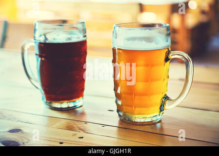 Coppe di luce e di birra scura su una tavola di legno su un pub sfondo. un assortimento di alcool in un volo pronto per la degustazione Foto Stock