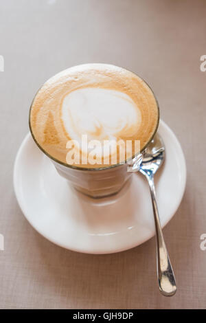 Un bicchiere di latte art caffè con forma di cuore sulla tavola in coffee shop. Foto Stock