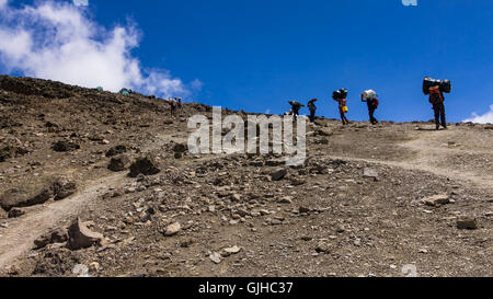 Facchini avvicinando Barafu Camp sul Monte Kilimanjaro, Tanzania Foto Stock