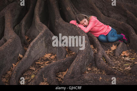 Ragazza distesa sul fico radici dormendo, Perth la Hyde Park, Perth, Australia Foto Stock