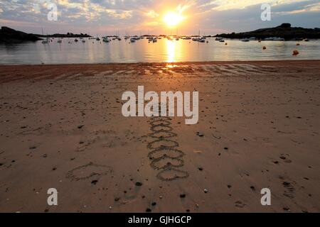 Cuori attirato nella sabbia sulla spiaggia al tramonto, Bretagna Francia Foto Stock
