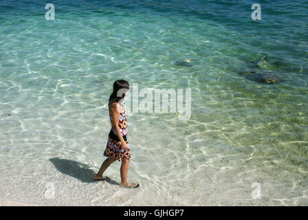 Donna che cammina lungo la spiaggia, Trogir, Dalmazia, Croazia Foto Stock