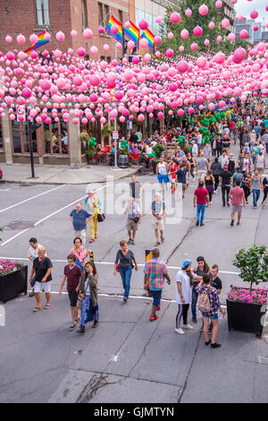 Montreal, CA - 14 agosto 2016: Rosa sfere attraverso Rue Sainte Catherine nel villaggio gay di Montreal con gay bandiere arcobaleno e Foto Stock