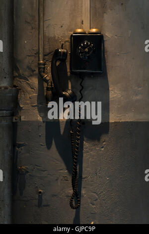 Un vecchio telefono nero appeso alla parete interna di un workshop Foto Stock