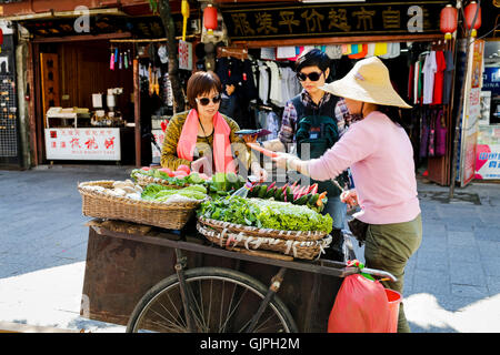 Una donna che vende le verdure fresche dal suo carrello sulla strada a Dali, Yunnan in Cina. Foto Stock