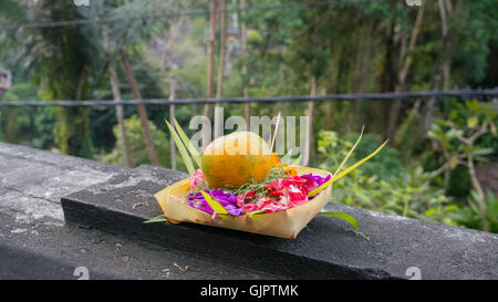 Un sano offrendo agli dèi di Bali con un mandarino e fiori (Canang Sari) Foto Stock