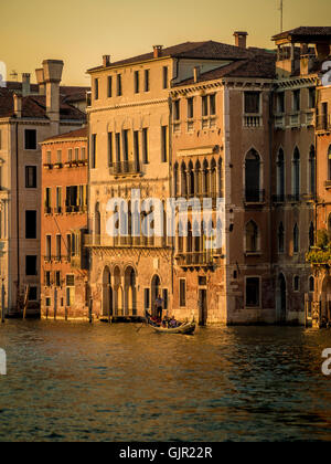 Single gondola sul Canal Grande al tramonto con edifici tradizionali in background, al tramonto. Venezia, Italia. Foto Stock