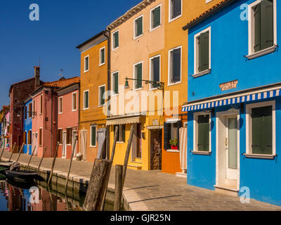 Case con terrazza in riva al mare dipinte con colori vivaci sull'isola di Burano. Venezia, Italia. Foto Stock