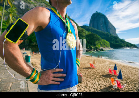 Medaglia d'oro atleta che indossa la tecnologia telefonica mobile armband sta ascoltando musica motivazionale in Rio de Janeiro, Brasile Foto Stock