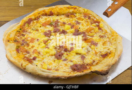 Pizza con pancetta e formaggio, pomodoro e ananas su metallo pizza spade Foto Stock