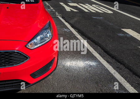 Una vista parziale di una nuova automobile rossa parcheggiato in strada. Foto Stock