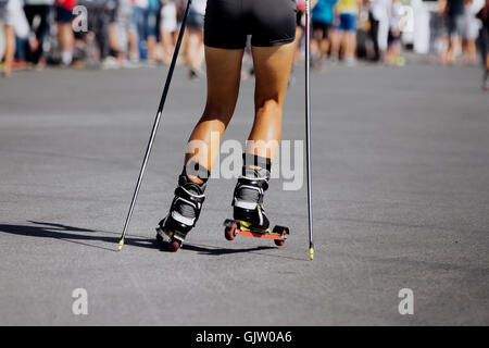 Piedi giovane atleta femminile in ski-rullo scorre su asfalto Foto Stock