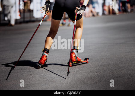 Gambe ragazza giovane atleta di sci-rullo scorre su asfalto Foto Stock