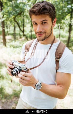 Bel giovane con zaino di scattare le foto con la vecchia foto fotocamera nella foresta Foto Stock