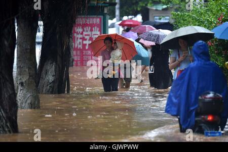 Haikou, cinese della provincia di Hainan. 18 Agosto, 2016. La gente a piedi in acqua in Haikou, capitale del sud della Cina di Hainan Provincia, e il agosto 18, 2016. Hainan è stata colpita dal tifone 'Dianmu','ottavo della stagione, con molte regioni saluto forti precipitazioni. Credito: Guo Cheng/Xinhua/Alamy Live News Foto Stock