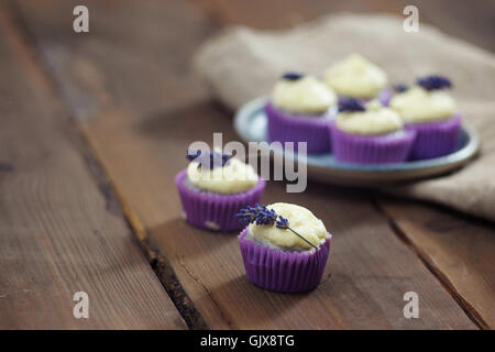 Lavanda mini tortine con mascarpone ciliegina sulla tavola di legno. Immagine ravvicinata con profondità di campo e un ampio spazio di copia. Foto Stock