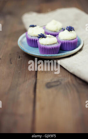 Lavanda mini tortine con mascarpone ciliegina sulla tavola di legno. Immagine ravvicinata con profondità di campo e un ampio spazio di copia. Foto Stock