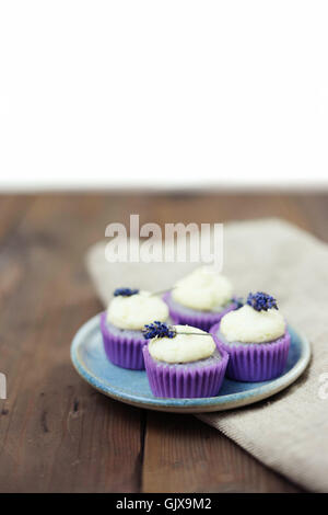 Lavanda mini tortine con mascarpone ciliegina sulla tavola di legno. Immagine ravvicinata con profondità di campo e un ampio spazio di copia. Foto Stock
