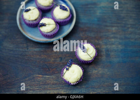 Lavanda mini tortine con mascarpone ciliegina sulla tavola di legno. Immagine ravvicinata con profondità di campo e un ampio spazio di copia. Foto Stock