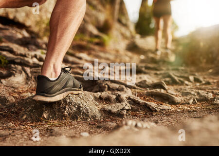 Primo piano dell'uomo trail running su terreno roccioso. Sezione bassa dei maschi di runner su cross country run. Foto Stock