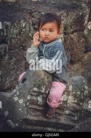 Angkor Wat, Cambogia - Agosto 2007: giovane ragazza seduta sulle rovine di uno dei templi di Angkor Wat complessa, Cambogia Foto Stock