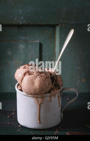 Congelati vintage tazza di alluminio con cioccolato fondente gelati sfere, servita con cucchiaio e cioccolato fondente tritato sul legno vecchio t Foto Stock