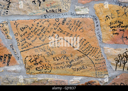 Visitatori scrawl messaggi sul recinto di pietra di fronte a Graceland, la casa di Elvis Presley e ora un museo a Memphis, Tennessee. Foto Stock