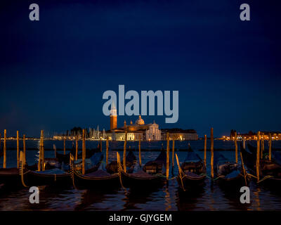 Gondole attraccate in San Marco con il Bacino di San Giorgio Maggiore in background, di notte. Venezia, Italia. Foto Stock
