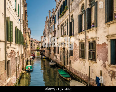 Barche ormeggiate su uno stretto canale con edifici tradizionali su entrambi i lati. Venezia, Italia. Foto Stock