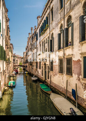 Barche ormeggiate su uno stretto canale con edifici tradizionali su entrambi i lati. Venezia, Italia. Foto Stock