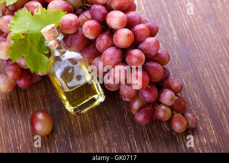 Piccola bottiglia con olio di semi di uva su una tavola di legno,fuoco selettivo Foto Stock