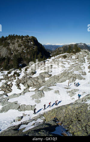 Più escursionisti Mount Seymour, British Columbia salendo al primo picco di vertice con una valle di montagna e cielo azzurro orizzonte Foto Stock